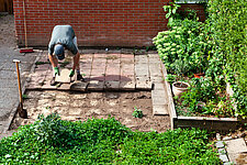 Een inwoner haalt tegels uit de tuin