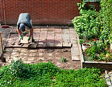 ontstenen van een achtertuin in Arnhem; removing tiles from a backgarden in Arnhem Een inwoner haalt tegels uit de tuin